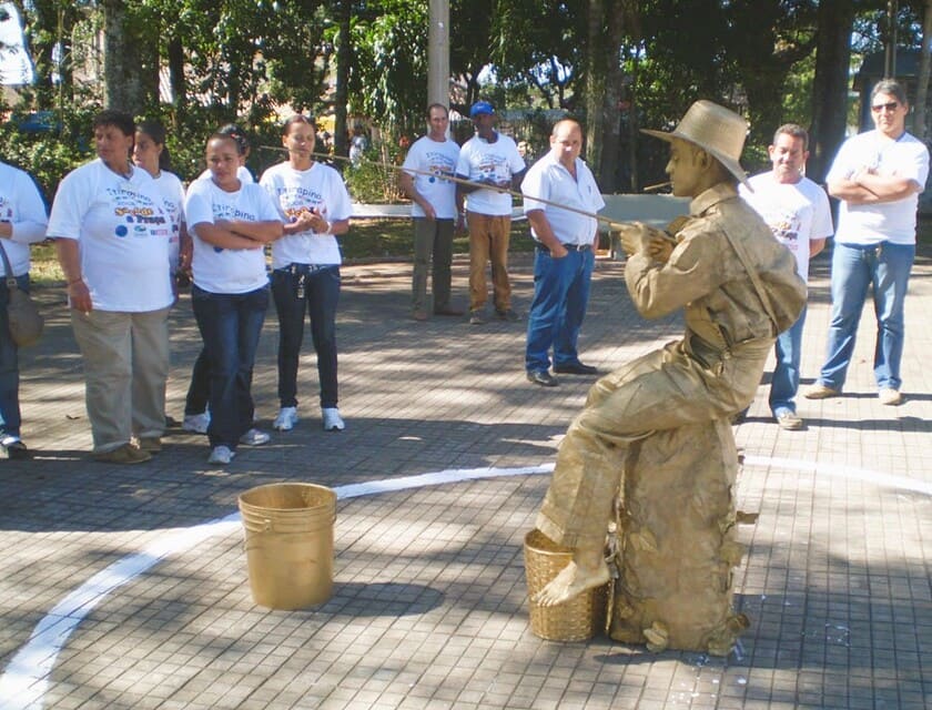 pescador dourado em praça publica e pessoas em volta olhando o trabalho da estatua viva