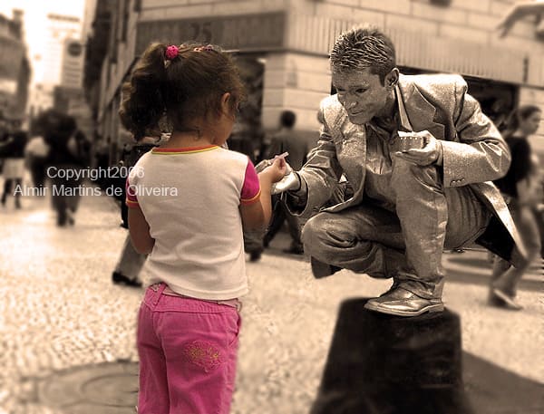 estatua viva prateada interagindo com uma criança no centro de sao paulo